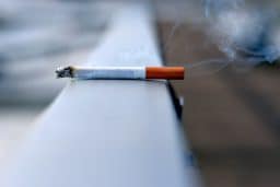 A lit cigarette sitting on a ledge.