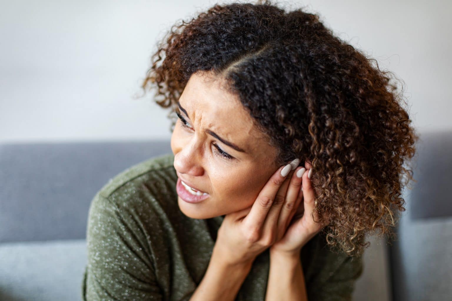 A woman experiencing ear and hearing discomfort.