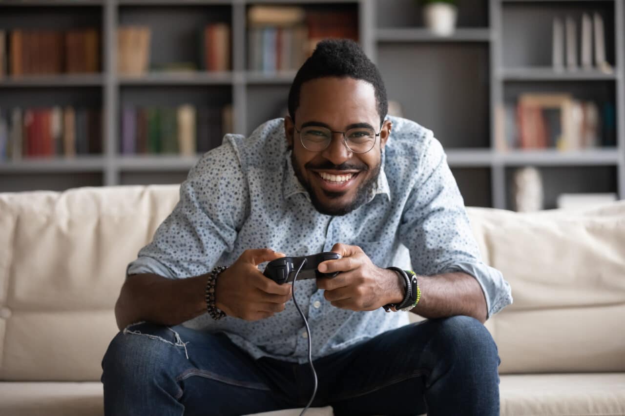 a man smiles as he holds a controller while playing a video game