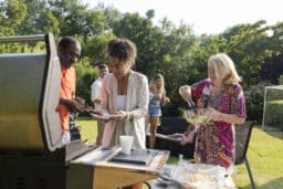 Man putting barbecue on woman's plate at a barbecue