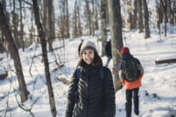 Smiling woman hiking through the snowy woods