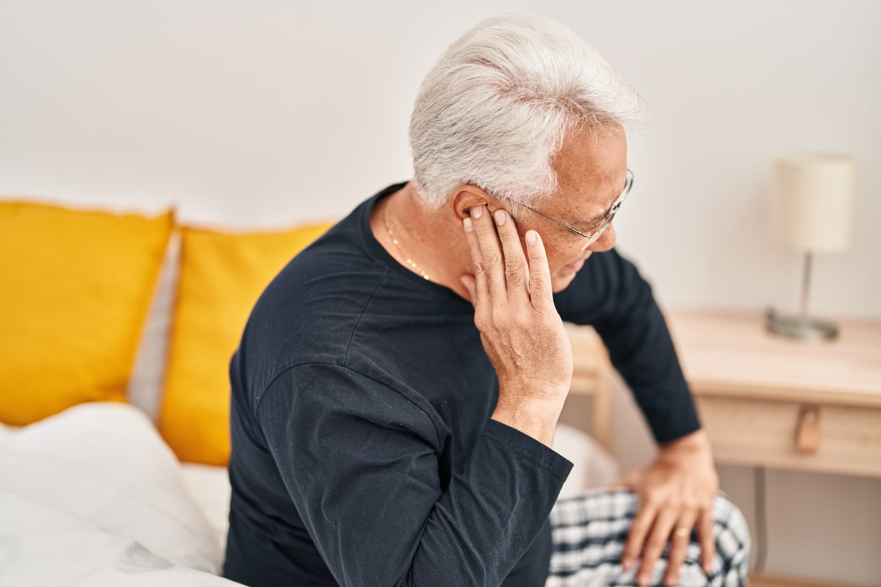 Man with ear pain holding his ear.