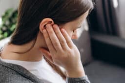 Woman with tinnitus holds ear